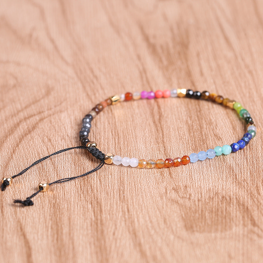 Seven chakras colored stones bracelet laid flat, multicolor beads with tied cord ends