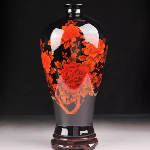 Ceramic vase with black background and orange floral pattern, glossy base.