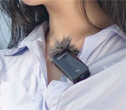 Clip-on wireless microphone with foam windscreen on a pale blue shirt